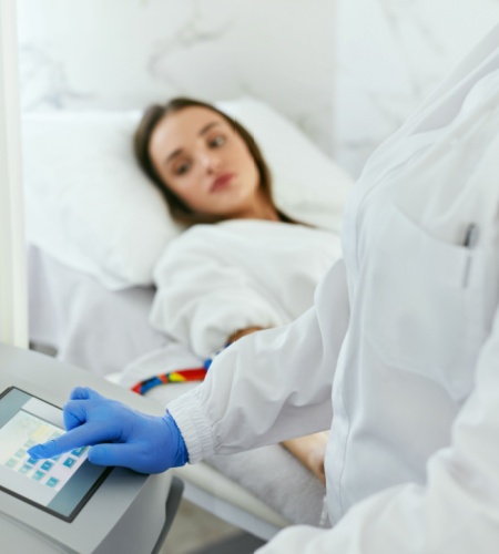 Eine Patientin liegt während einer Ozontherapie-Sitzung, die von einem medizinischen Fachpersonal überwacht wird. Diese Therapie wird zur Behandlung von entzündlichen Erkrankungen und zur Verbesserung der Durchblutung eingesetzt.