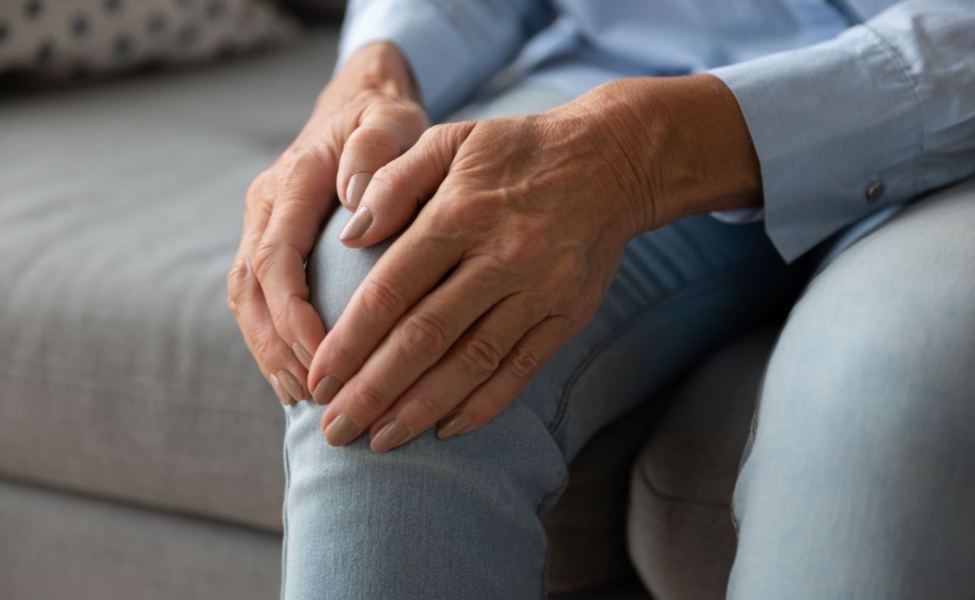 Nahaufnahme der Hände einer älteren Person, die ihr schmerzendes Knie umfasst. Der Artikel behandelt ganzheitliche Therapieansätze gegen Arthrose, von klassischen bis komplementären Methoden, um Schmerzen zu lindern und das Fortschreiten der Erkrankung zu verhindern.