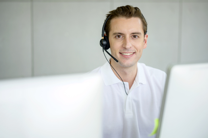Ein freundlicher Kundendienstmitarbeiter von Naturheilverfahren.de mit Headset vor einem Computerbildschirm.