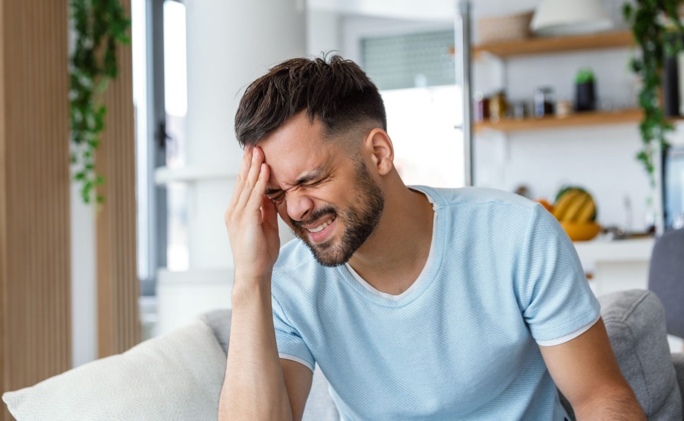 Mann mit Migräne hält sich vor Schmerzen den Kopf. Der Artikel untersucht die Wirksamkeit komplementärer Therapien zur Migränebehandlung, die oft als Ergänzung zu medikamentösen Methoden gesucht werden.