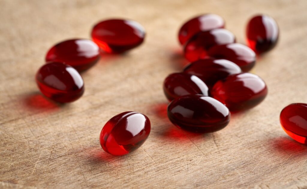 Rote Krillöl-Kapseln auf einem Holztisch, die für ihre entzündungshemmenden Eigenschaften bekannt sind, jedoch laut einer aktuellen Studie keine signifikanten Vorteile bei der Behandlung von Kniearthrose bieten.