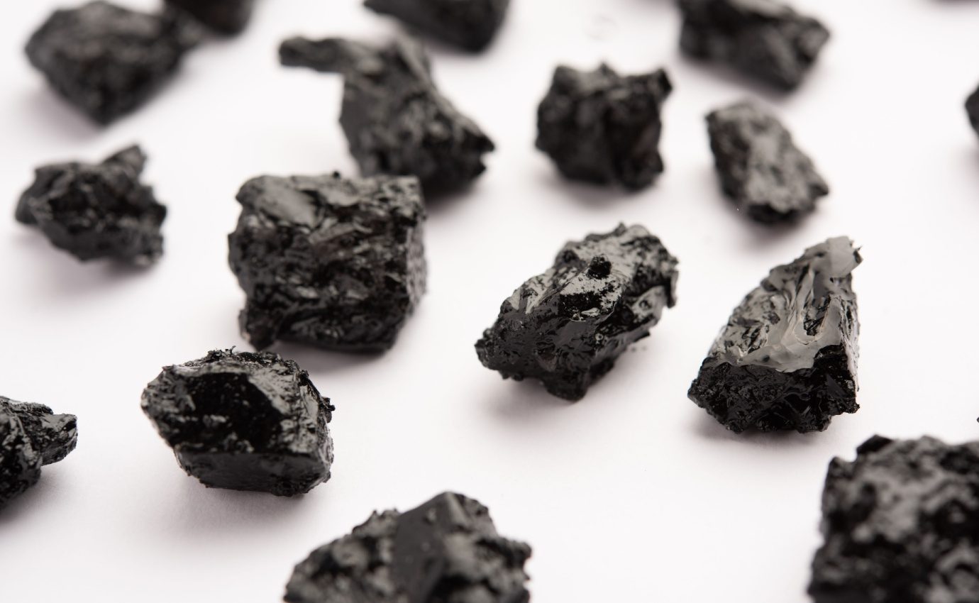 Shilajit-Stücke in bräunlich-schwarzer, harziger Konsistenz, ein traditionelles Heilmittel aus den Himalaya-Bergen, das für seine gesundheitlichen Vorteile wie antioxidative, entzündungshemmende und energiefördernde Eigenschaften geschätzt wird.