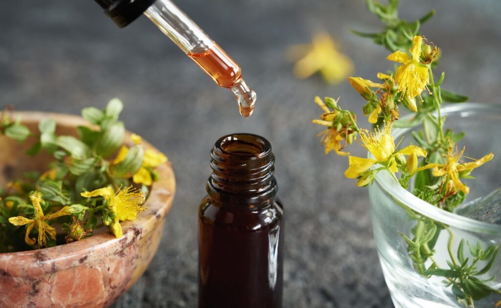 Johanniskrautblüten und -öl in Nahaufnahme: Die gelben Blüten und das konzentrierte Öl symbolisieren die natürliche Heilkraft der Pflanze, die bei leichten bis mittelschweren Depressionen eingesetzt wird.