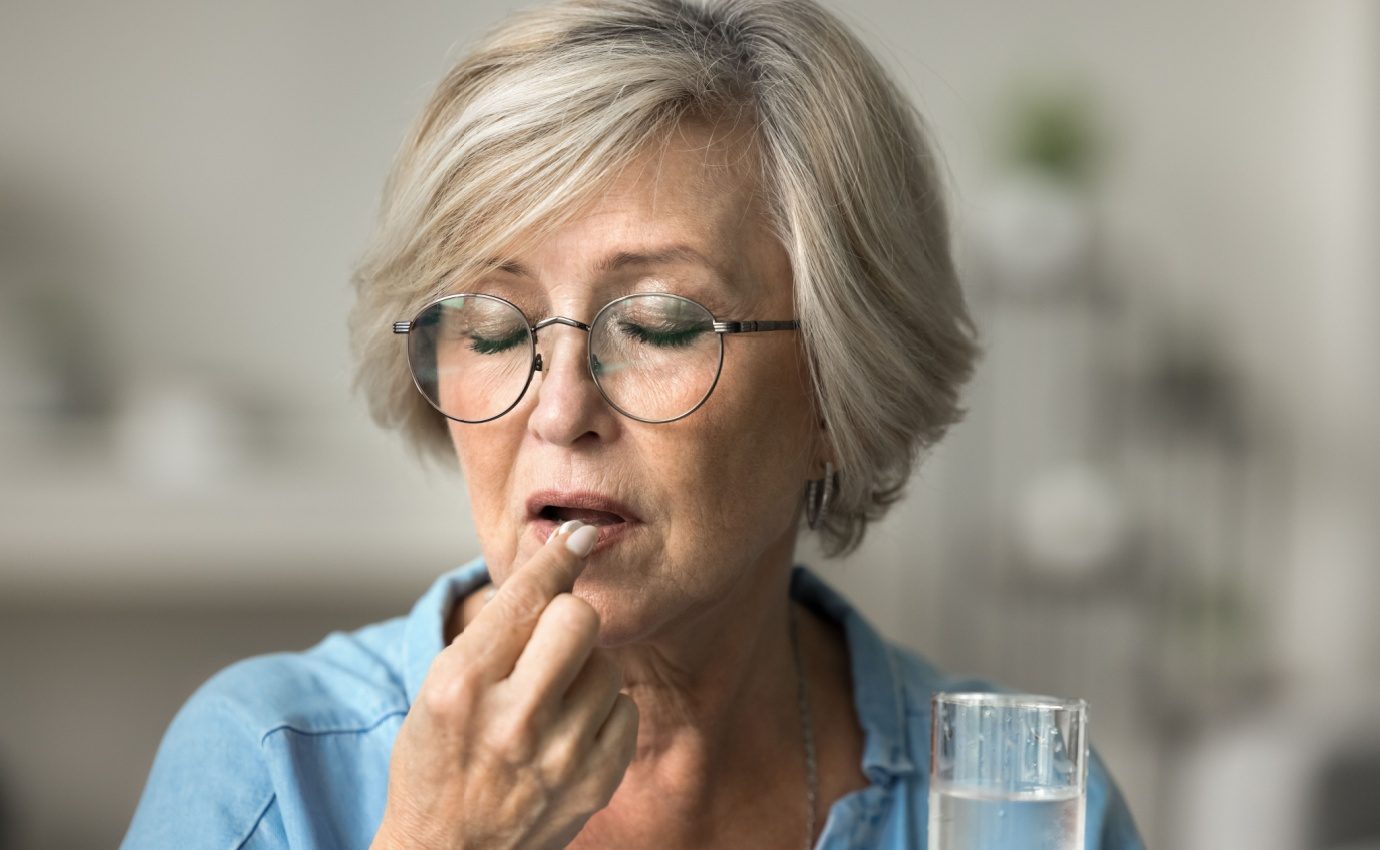 Ältere Frau nimmt eine Multivitamin-Tablette ein – Studie zeigt mögliche Effekte von Multivitaminen auf die kognitive Gesundheit im Alter.