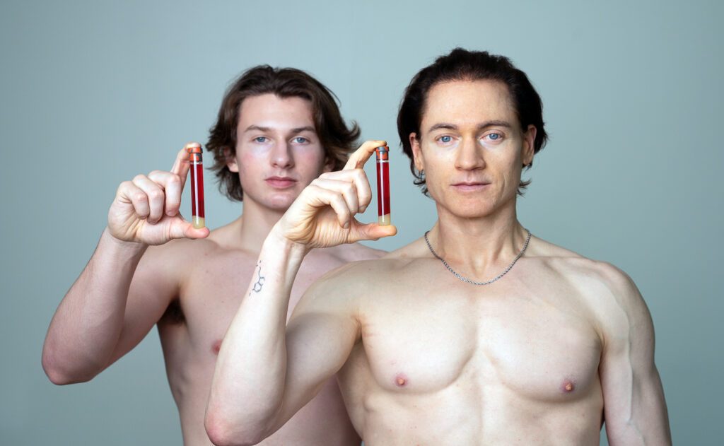 Bryan Johnson und sein Sohn halten Blutproben in die Kamera – ein Sinnbild für die radikalen Methoden der Longevity-Pioniere. Der Artikel beleuchtet unterschiedliche Ansätze der Langlebigkeitsforschung und ihre wissenschaftliche Basis.