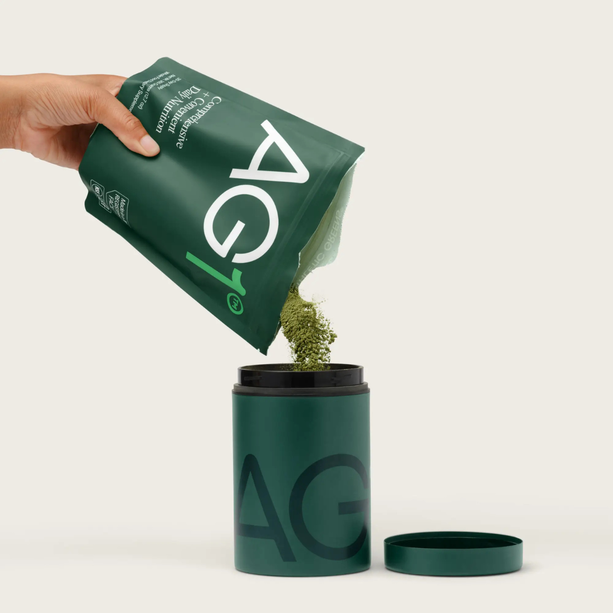 AG1-Pulver wird aus Nachfüllpackung in Vorratsdose gefüllt – nachhaltige Anwendung des Superfood-Supplements
