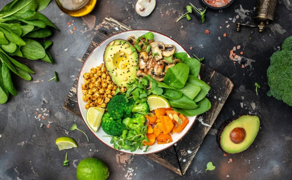 Bunt angerichtete vegane Bowl mit Brokkoli, Spinat, Avocado, gerösteten Kichererbsen und Süßkartoffeln – gesunde pflanzliche Ernährung für Herz, Gewicht und Stoffwechsel.