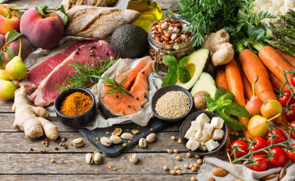 Frische Zutaten der mediterranen Ernährung – Lachs, Olivenöl, Hülsenfrüchte, Vollkornbrot, Gemüse, Obst, Nüsse und Kräuter als Grundlage der Mittelmeerdiät.