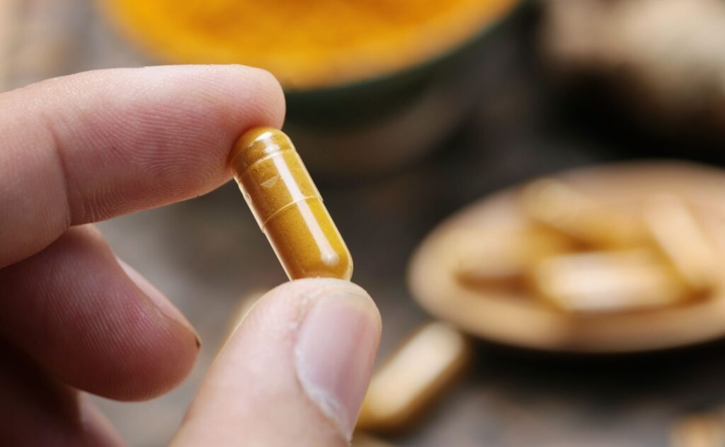Kurkuma-Kapsel mit Curcumin in der Hand – Studien zeigen leichte Gewichtsabnahme bei Typ-2-Diabetes durch Curcumin-Präparate.