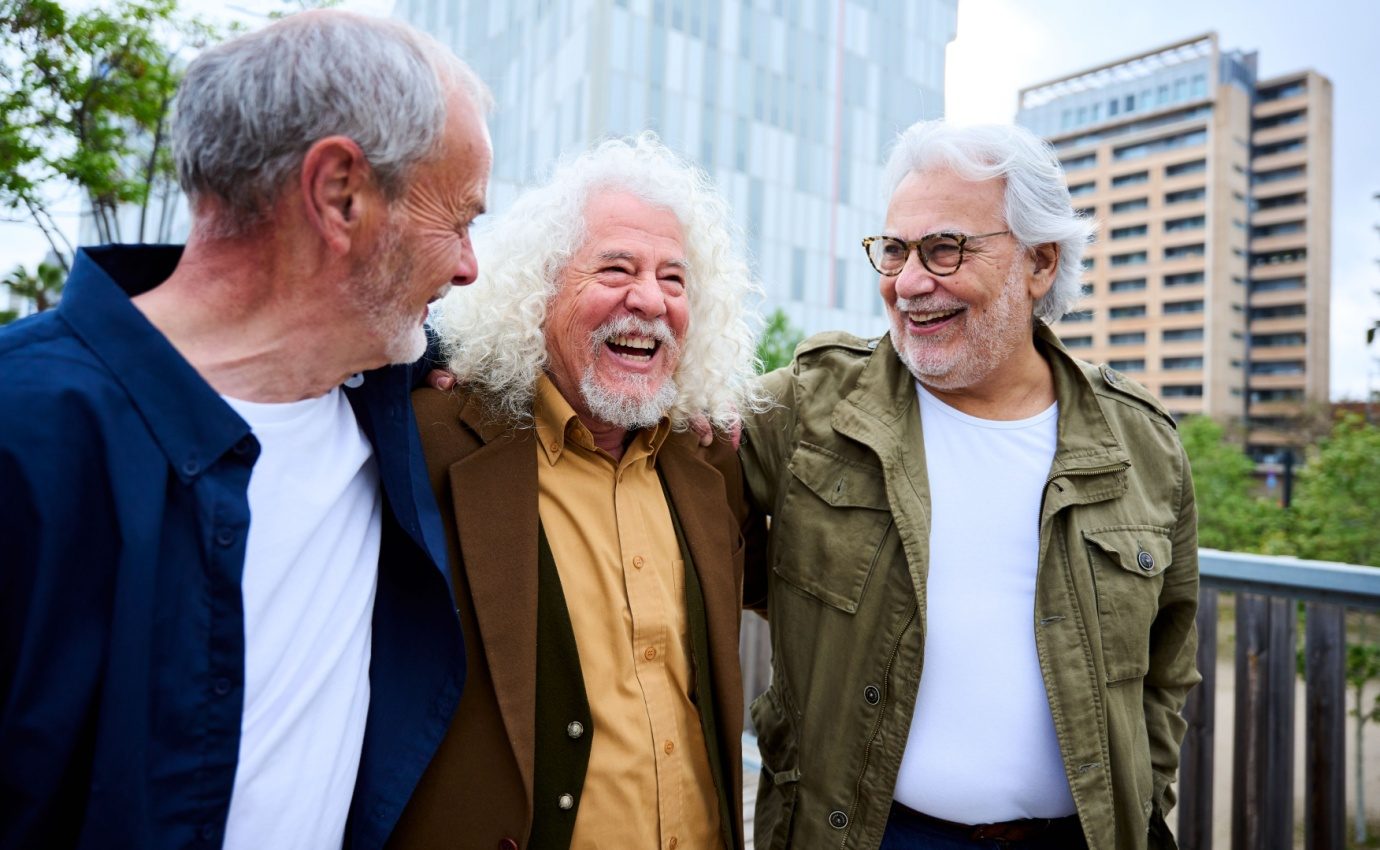 Drei fröhliche ältere Männer lachen gemeinsam im Freien – Symbol für mentale Fitness, soziale Verbundenheit und gesundes Altern bei sogenannten Super-Agern.